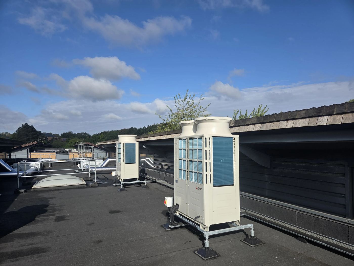 Mitsubishi Electric outdoor units on galvanised frames with anti-vibration mounts, set level on the existing roof.